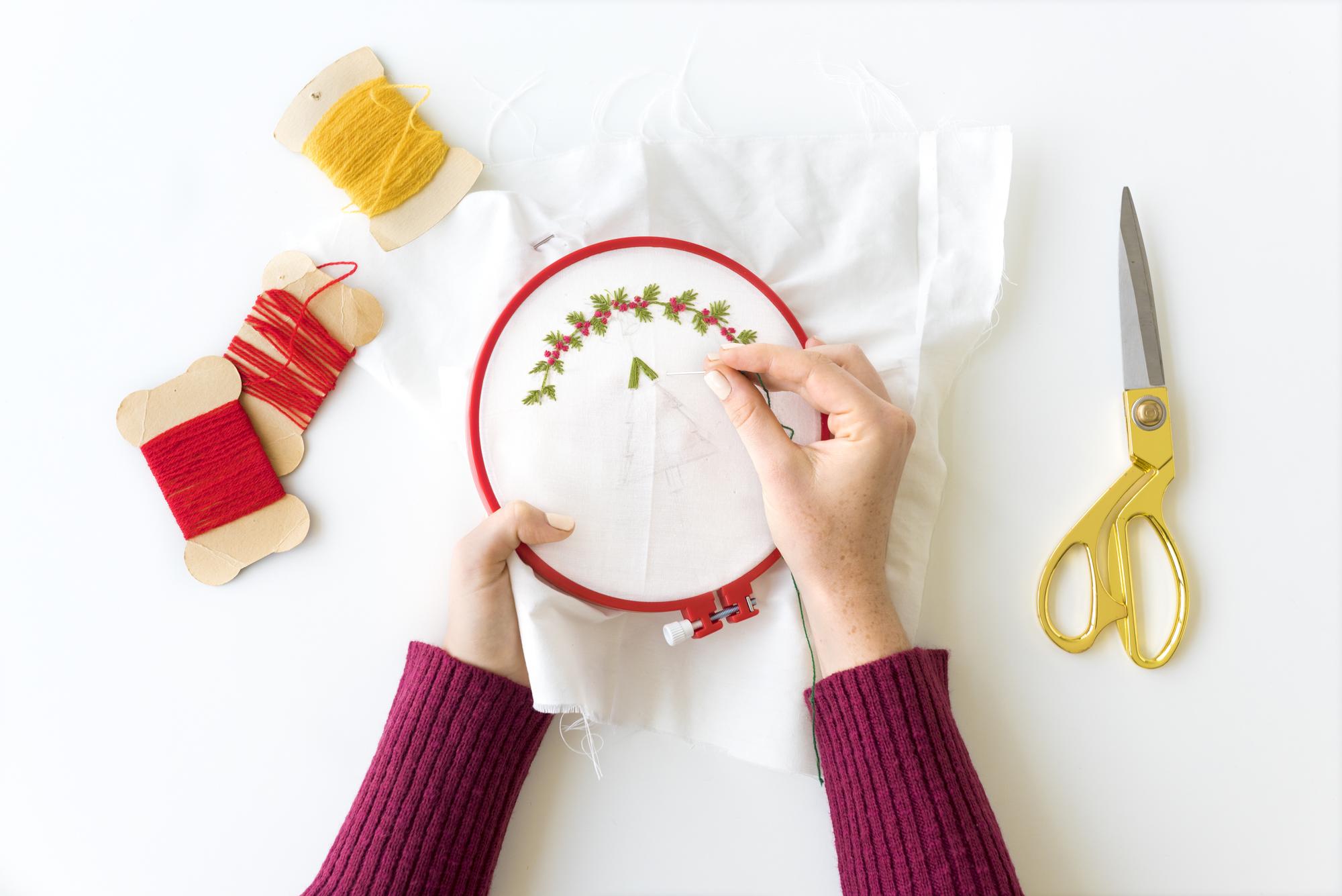 hands arranging embroidered samples on table